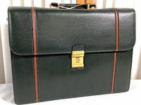 Front view of dark green textured leather briefcase with brown trim and gold-tone combination lock labeled Bally.