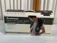 Front view of the product box with image of model wearing the massager and key features listed.