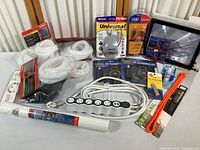 Full view showing all items including white cable channels, power strip, card reader, cleaning kits, cable ties, and magnifying frame