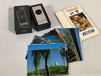 Photo showing the translator device in its original black box, souvenir postcards spread out, and the Beijing travel booklet.