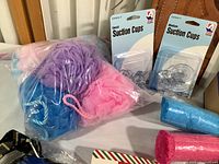 Multiple colorful shower scrubs and two packages of suction cups (small and medium) on table.