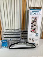 Photo showing black velvet hangers both multi-tiered and single, a clear cosmetics organizer, two small clear plastic holders, and a boxed over-the-door shoe rack for 36 pairs of shoes.