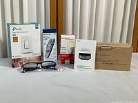 Two boxed Aooteck 48 LED solar motion sensor lights, TP-Link smart WiFi light switch box, Sengled smart LED bulb box, Keepro reading light box, and +2.5 power reading glasses in plastic sleeve.