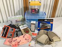 Overview of all items: four pairs of socks with varied designs, toothpaste dispenser, stapler, two storage boxes, beige travel slippers in a beige drawstring bag, and boxed anti-age serum.