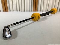 Full view of Momentous weighted golf swing trainer showing metal club head and weighted handle