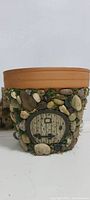 Front view of the pot showing miniature round door surrounded by small stones and faux moss