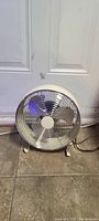 Photo of the electric fan on floor showing entire fan with metal blades and grille