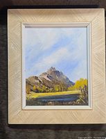 Full view of the acrylic painting mounted in a textured cream frame with white inner border showing a mountain landscape.