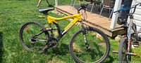 Left side profile view of used 26 inch Supercycle Menace mountain bike showing yellow and black frame, front and rear tires, seat and handlebars