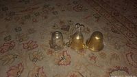 Photo of three antique silver plated bells arranged on a patterned carpet.