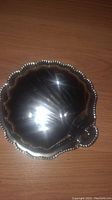 Closed view of the silver plated shell-shaped trinket box showing beaded edges and shiny silver surface.