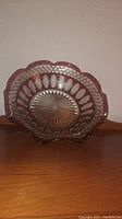 Clear front view of glass candy dish showing scalloped rim, textured oval pattern, and starburst detail in base.