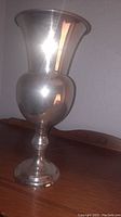 Front angled view of silver plated vase showing bulbous body, flared mouth, and pedestal base.