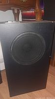 Front view of black Henry Kloss speaker cabinet with metal mesh grille covering speaker.