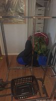 Full front view of the metal clothes rack showing rectangular frame and bar for hanging clothes, with visible rust and wear.