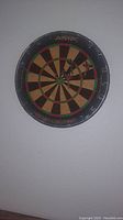 Full view of AMF dart board mounted on wall with multiple darts inserted, showing usage.