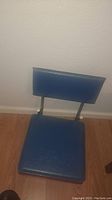Blue padded seat with a slightly angled backrest visible from one side