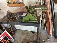 Side angle view of Central Machinery belt and disc sander mounted on a metal stand in workshop.