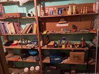 Wooden shelves filled with books, hardware items, and tools. Various small boxes and decor items visible.
