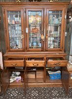 Full view of the wooden china cabinet with glass doors opened and drawers pulled out showing storage compartments below.