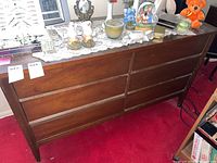Full front view of the wooden dresser with 6 drawers and several decorative items on top, showing the exterior finish and style.