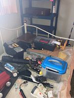 Photo showing several plastic tackle boxes, fishing line spools, assorted fishing tools, and equipment placed on a bed.
