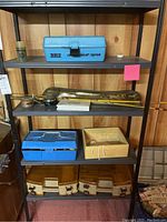 Shelving unit with fishing gear including rods, reels, tackle boxes, and blue Teco Junior Air Tester box