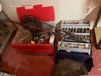 Overall view of fishing rods, large plastic bin and tackle box with contents