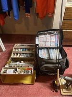 Tackle box, black fly fishing case, and fly fishing rod with reel set arranged on carpet.