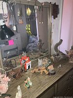Wide view of mirror reflecting various decor items and fishing lures on top of wooden dresser including figurines and wood sculptures