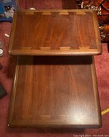 Two rectangular tabletops stacked, showing wood grain and dovetail inlay edges