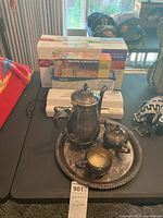 Photo of the tea set on the round tray along with boxed Seal-a-Meal food saver and recipe converter box on black table.