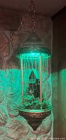 Front view showing entire hanging lamp illuminated with ambient green light.