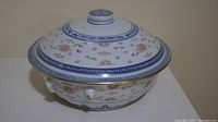 Side view of the porcelain soup tureen showing the gold gilded dragon motif and floral designs with lid on top.