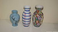 Three ceramic vases shown side by side on a beige surface against a light wall for size and condition reference.