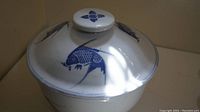 White ceramic lidded dish displaying blue fish design on the lid and sides.