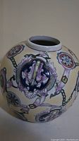 Close-up showing the detailed floral medallion pattern on the vase with blue, purple, green, and red colors on a white background.