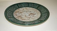 Single large decorative plate, 12 inch diameter, with bronze colored chariot and horse design and green geometric border.