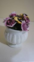 Porcelain flower vase showing white porcelain base with sculpted design and multicolor porcelain flowers on top.