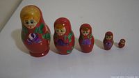 Photo showing all five Russian nesting dolls lined up from largest to smallest on a white surface
