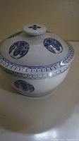 Side view of the vintage blue and white porcelain lidded dish showing crane motifs and decorative border.