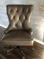 Front view of chair showing tufted back, seat cushion and wood base