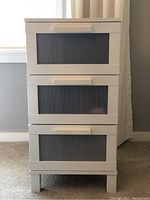 Front view showing all three drawers with ribbed translucent panels and white handles.