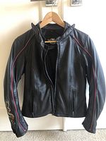 Front view of the black Harley Davidson women's leather jacket with red piping and zip-up pockets.