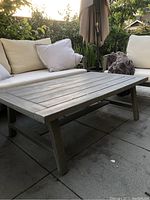 Outdoor seating area with gray San Sebastian coffee table centered among cushions and pillows.