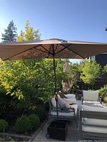 Full view of the rectangular beige patio umbrella open on a patio with surrounding outdoor furniture.