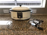 Front view of Nesco 6 quart white roaster oven on countertop showing temperature dial, power cord, and metal roasting rack.
