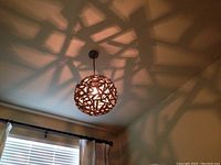 The driftwood chandelier hanging from the ceiling, illuminated and casting intricate shadows on the ceiling and walls.