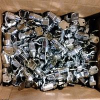 Box containing over 90 chrome cabinet locks with attached keys in a jumble, showing quantity and finish.