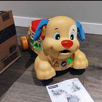 Fisher-Price Laugh & Learn Stride-to-Ride Puppy toy front view with instruction sheet and original box partially visible.